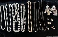 Full lot overview showing all necklaces and earrings on black background