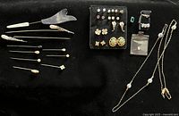 Overview of hat pins, earring board, rings and necklace on black background