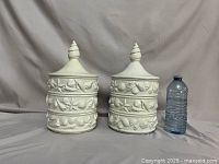 Two stacked sets with lids beside water bottle for scale