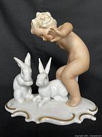 Front view of porcelain cherub with two rabbits on gilt-edged base