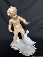 Front view of porcelain cherub and goose figurine on shaped base