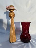 Front view of straw doll and ruby vase