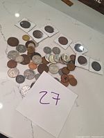Coins displayed on a white counter, showing a mix of copper and silver-colored coins, several older large coins in holders.