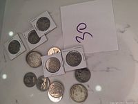 Photo showing a mix of Canadian 50 cent coins, some in protective holders and some loose, arranged on a surface.