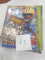 Photograph of vintage football magazines and booklet, showing a colorful magazine with NFL players and a smaller black and white Pro Football Heroes booklet on top.