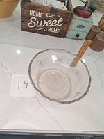 Glass punch bowl on a white countertop with a measuring ruler inside showing the size approximately 6 inches high.