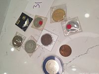 All medallions and coins arranged on a white surface, showing various sizes and packaging.
