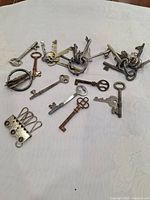 Full spread of old keys and keyrings on a light fabric surface, showing variety and condition