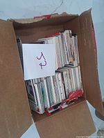 Cardboard box with a large number of loosely packed sports trading cards, note the box is worn with torn edges.