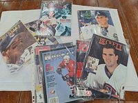 Top view of assorted sports magazines with hockey and baseball players on the covers, magazines are in plastic sleeves.