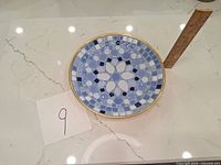Top-down photo of a circular dish with a blue mosaic pattern and gold rim. A ruler is placed beside for size reference.