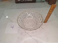 Top-down view of the clear vintage glass bowl showing the textured geometric exterior and starburst pattern inside, with a ruler for scale.