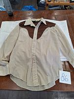 Full front view of beige checkered Western style shirt with brown yoke and collar spread out flat on table for condition review.