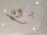 Five vintage watch faces including four wristwatches and one pendant watch on a white marble background.