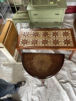 Overview of three tables: folding wood table, tile inlay coffee table, and crescent demi-lune table with worn top