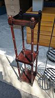 Dark stained wooden 3 tier plant stand with turned legs and finial details