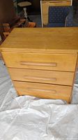 Front view of wooden chest of drawers with 3 drawers and horizontal wood handles.