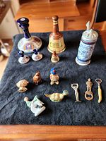 Photo showing all whiskey bottles, ceramic stein, miniatures, and bottle openers on black cloth.
