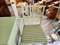 Photo showing green painted wooden chair with patterned cushioned seat next to the green chest.