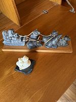 Overall view of two soapstone carvings including a large gray husky dog team on wood base and a small white carving on slate base