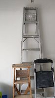 Photo showing aluminum step ladder, wooden step stool, and aluminum two-step stool arranged side by side.