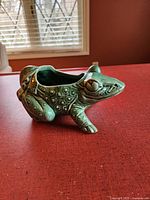Side view of green frog planter showing detailed texture and hollow center