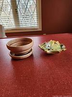 Image showing brown round 5-inch planter with matching saucer next to green/yellow leaf-shaped wall mounted planter