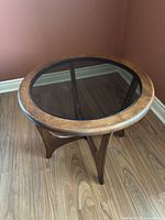 Side angle view showing the oak frame, smoked glass top, and sculpted legs with cross support.