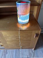 Full view of the Niagara Falls table lamp illuminated on a wooden surface, showing the waterfall artwork clearly.