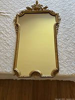 Full view of the ornate gold wooden framed mirror showing overall shape and decorative details