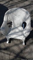 Front view of the child sized white wicker rocking chair showing woven wicker design and rocking base.