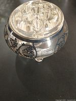 Close-up of a small painted crystal vase with black floral designs on clear glass base