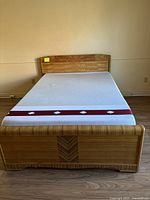 Full view of the vintage wooden bed frame with mattress, showing headboard and footboard with herringbone wood grain pattern
