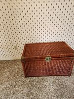Front view of the closed large wicker chest showing the woven wicker texture and brass latch lock.