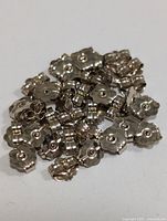 Close-up image displaying a pile of small 10KT gold earring backs with scalloped edges and central holes.