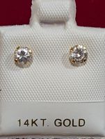 Front view of 14KT gold stud earrings showing clear round cubic zirconia stones in prong settings on white earring card labeled '14KT GOLD'.