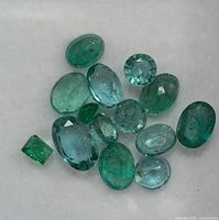 Close-up of genuine emerald gemstones showing faceted cuts and green hues.