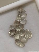 Multiple loose genuine Zultanite polished cabochon gemstones laid out on white background