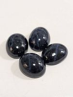 Four polished star sapphire cabochon gemstones arranged on a flat surface showing their color and star effects.