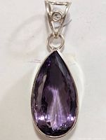 Close-up front view of the silver pendant featuring a large, faceted teardrop amethyst set in a bezel.