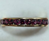 Close-up photo of the ring side showing the row of round garnet gemstones set in silver band.