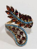 Silver ring with marquise garnet stones and turquoise beads, shown from a top and angle view to display the detailed design and stone settings.