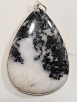 Close-up image of the front side of the teardrop-shaped silver pendant with black and white marbled gemstone showing its polished surface and silver bail.