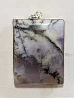 Front view of rectangular gemstone pendant with natural white, grey and black veining, set in silver.