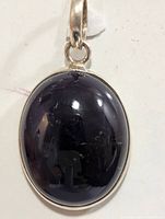 Front view of oval silver pendant with shiny dark genuine gemstone showing smooth cabochon surface.