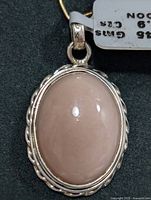 Close-up image of oval moonstone pendant in silver twisted rope design bezel with attached silver bail showing polished stone surface and bright silver finish.