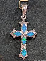 Top down photo of one silver opalite cross pendant showing all five diamond-shaped blue-green opalite stones and quatrefoil decorative silver edges on the cross