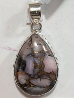 Front close-up of the teardrop Mohave turquoise pendant showing pink and gray stone with copper matrix set in silver.