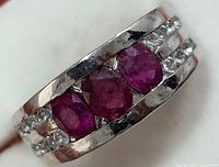Close-up image showing the front face of the sterling silver ring with three red ruby stones flanked by cubic zirconia.