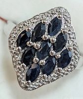 Close-up image of the silver ring showing marquise-cut blue sapphires and surrounding silver bead accent border.